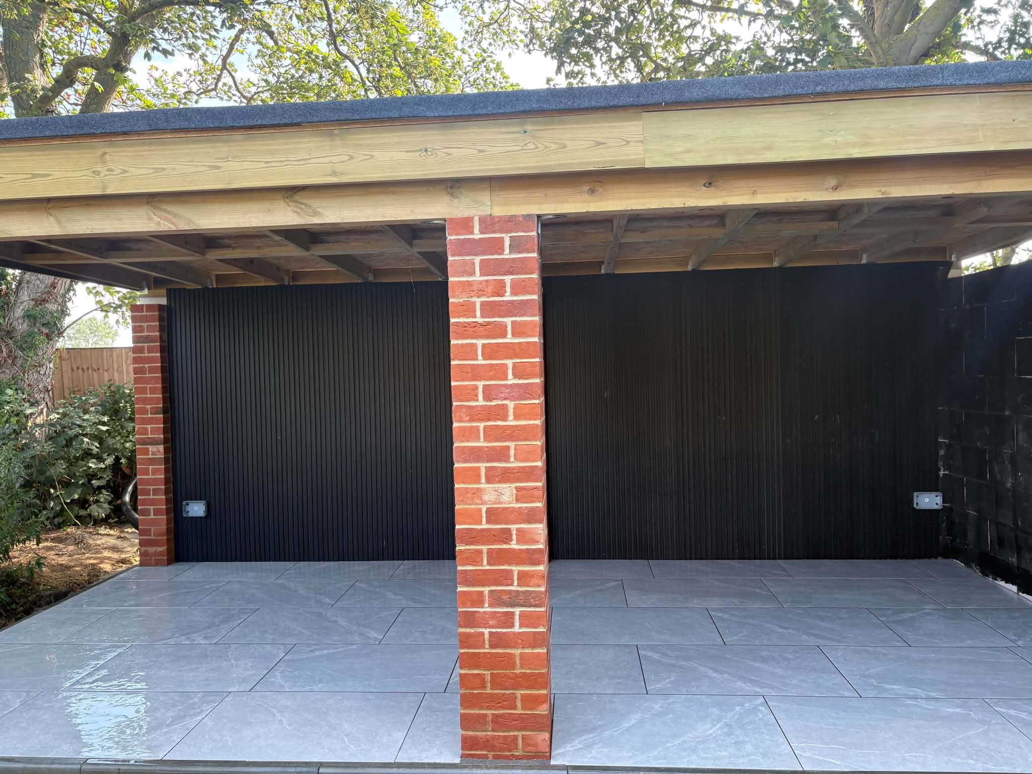 Completed grey porcelain patio beneath a timber garden structure